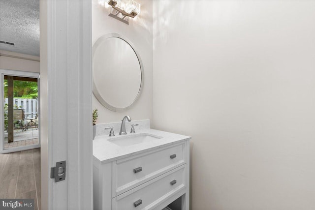bathroom with a textured ceiling, vanity, and wood finished floors