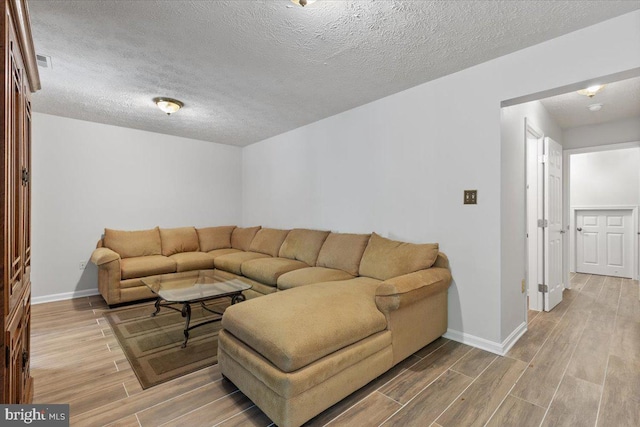 living area with wood finished floors, baseboards, and a textured ceiling