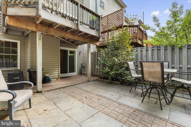 view of patio featuring fence, outdoor dining area, and a wooden deck
