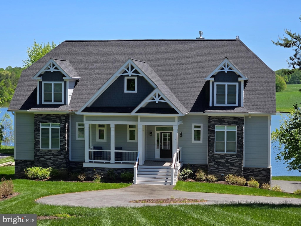 craftsman inspired home featuring covered porch, stone siding, and a front lawn