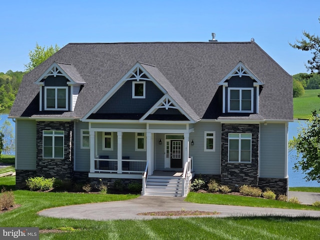 craftsman inspired home featuring covered porch, stone siding, and a front lawn