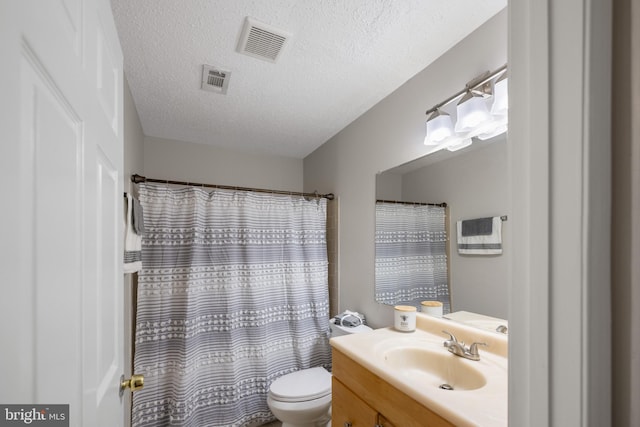 bathroom featuring vanity, toilet, a textured ceiling, and visible vents
