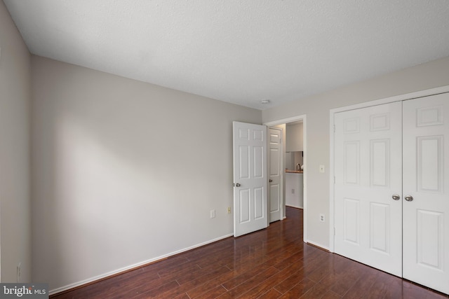unfurnished bedroom with baseboards, a closet, and dark wood-style floors