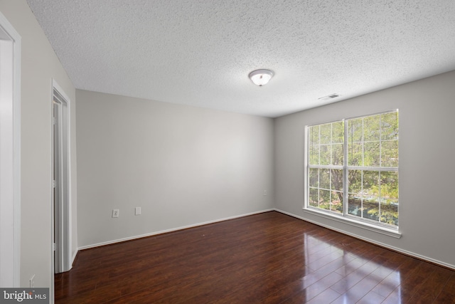 empty room featuring hardwood / wood-style flooring, a textured ceiling, and visible vents