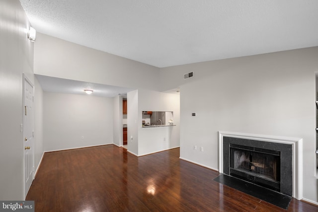 unfurnished living room featuring baseboards, visible vents, a fireplace with flush hearth, and wood finished floors