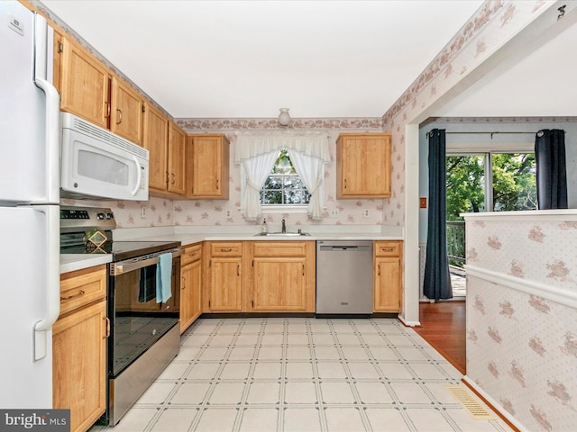 7250 Single Wheel Path, Columbia, MD 21046 - kitchen featuring appliances with stainless steel finishes, wallpapered walls, light flooring, plenty of natural light, and a sink