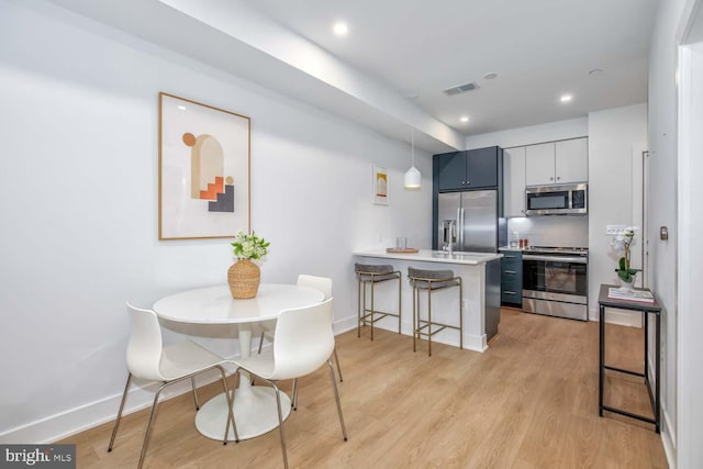 2310 4th St NE Unit 5, Washington, DC 20002 - kitchen featuring stainless steel appliances, a breakfast bar, visible vents, light wood-style floors, and a peninsula