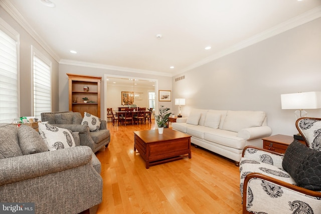living room featuring visible vents, plenty of natural light, ornamental molding, and light wood finished floors