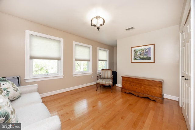 sitting room featuring visible vents, light wood-style flooring, and baseboards