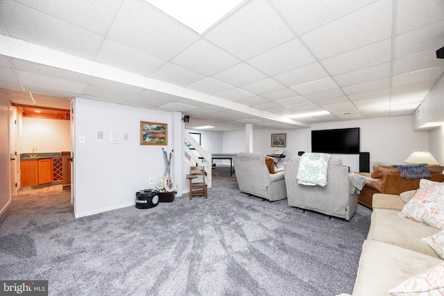 living room with baseboards, carpet flooring, and a drop ceiling