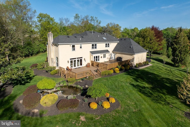 back of property featuring a lawn, a deck, a chimney, and stucco siding