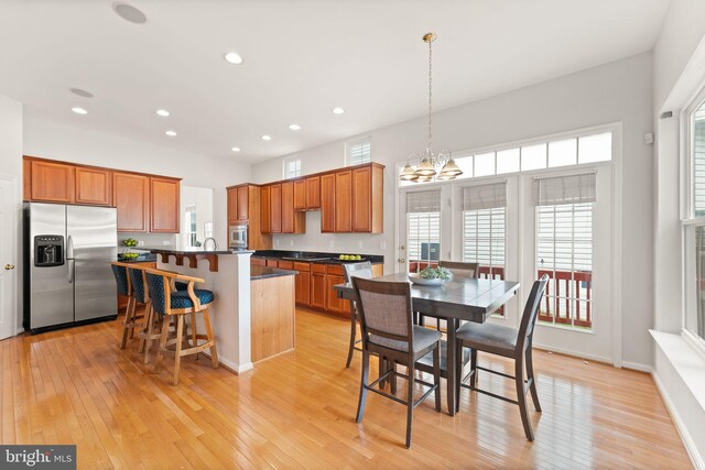 17435 Lethridge Cir, Round Hill, VA 20141 - kitchen featuring stainless steel appliances, light wood-style floors, a kitchen island, a kitchen breakfast bar, and dark countertops