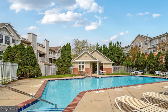 pool with a patio, fence, and a residential view