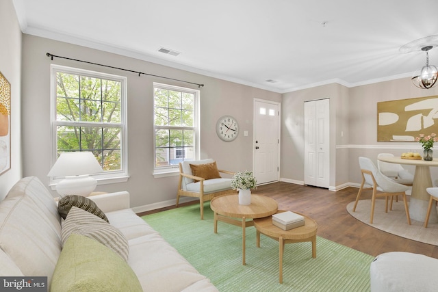 living room with visible vents, crown molding, an inviting chandelier, wood finished floors, and baseboards