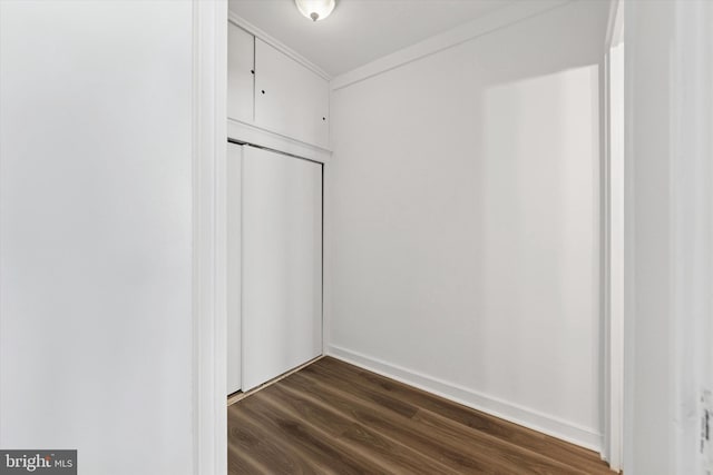unfurnished room featuring baseboards, ornamental molding, and dark wood-type flooring