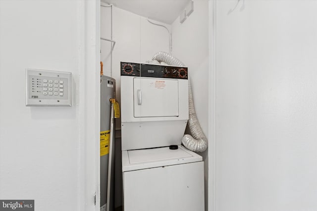 clothes washing area with stacked washer and dryer, laundry area, and water heater