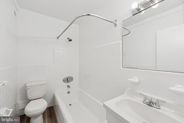 full bathroom with shower / bath combination, a sink, toilet, and tile walls