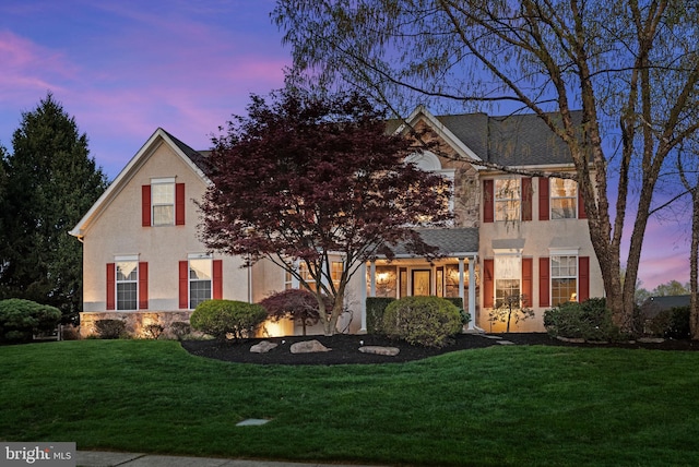 view of front facade with a lawn, stone siding, and stucco siding