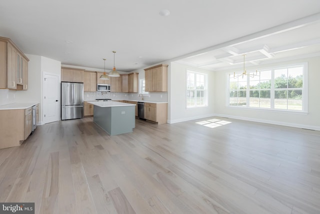 kitchen with light brown cabinetry, an inviting chandelier, a kitchen island, light wood-style flooring, and appliances with stainless steel finishes