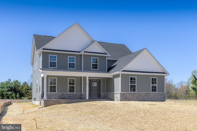 craftsman-style house featuring roof with shingles, stone siding, and covered porch