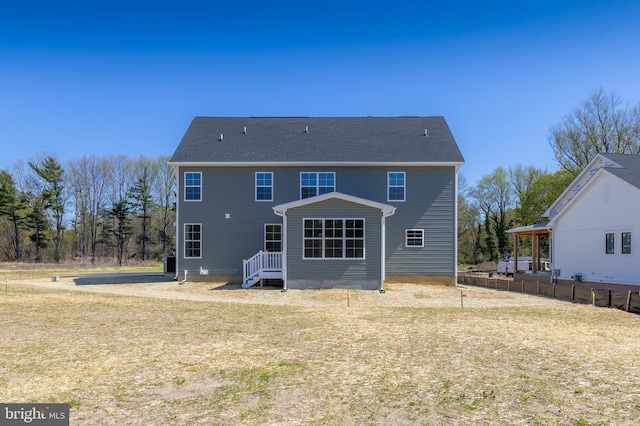 rear view of property featuring fence and a lawn