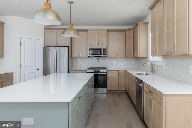 kitchen featuring stainless steel appliances, light countertops, wood finished floors, a sink, and tasteful backsplash