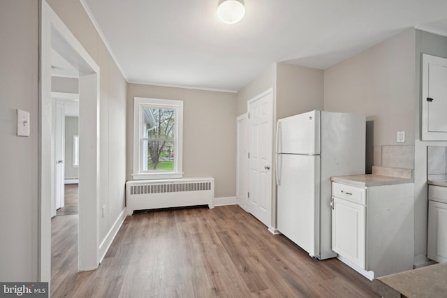 673 Harrisonville Rd, Swedesboro, NJ 08085 - kitchen featuring white cabinets, light wood-style floors, light countertops, radiator, and freestanding refrigerator
