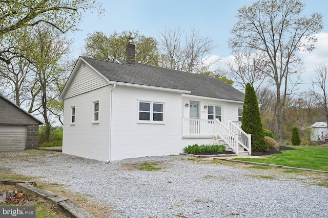 673 Harrisonville Rd, Swedesboro, NJ 08085 - view of front of house with a chimney, an outdoor structure, concrete block siding, and a shingled roof