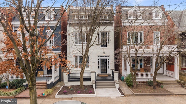 multi unit property with brick siding, mansard roof, and covered porch