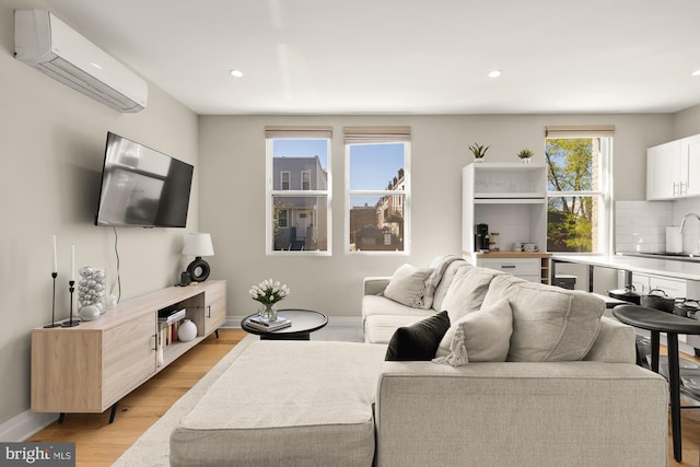 living area featuring recessed lighting, light wood-style floors, baseboards, and an AC wall unit