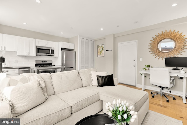 living area featuring light wood-style floors, baseboards, and recessed lighting