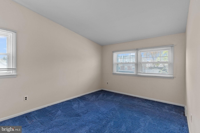 empty room featuring dark carpet and baseboards