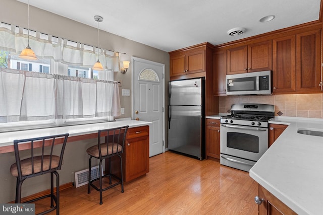 kitchen with stainless steel appliances, light countertops, visible vents, and brown cabinets