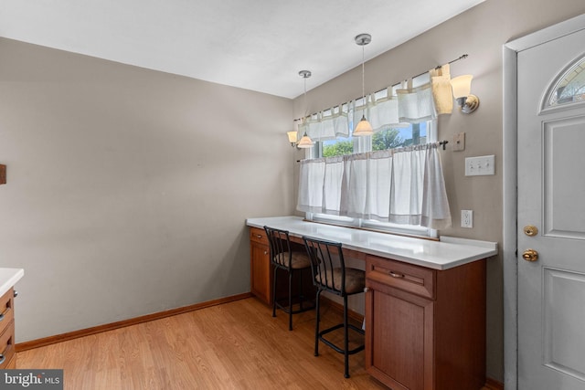office space with light wood-style floors, built in study area, and baseboards