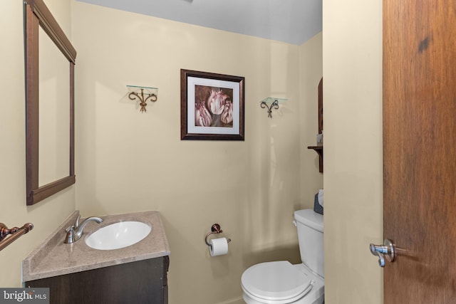 half bath with baseboards, toilet, and vanity
