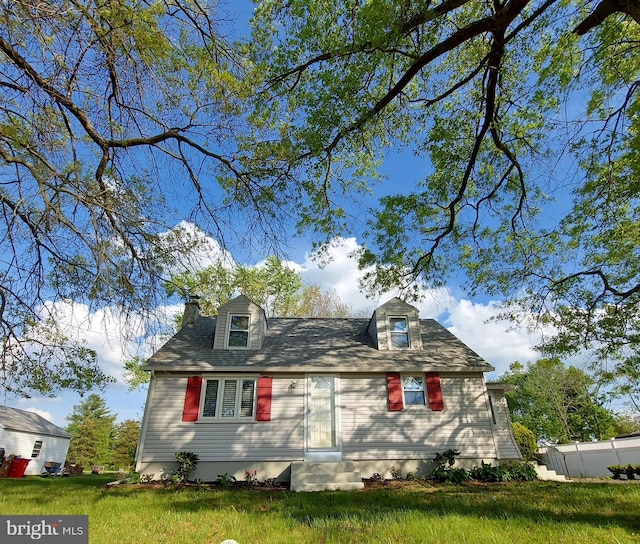 cape cod house with fence, a chimney, and a front yard