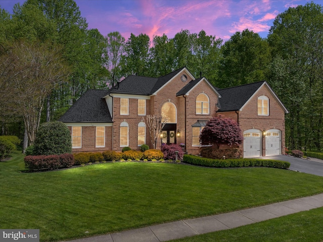view of front of home featuring roof with shingles, a garage, brick siding, aphalt driveway, and a yard