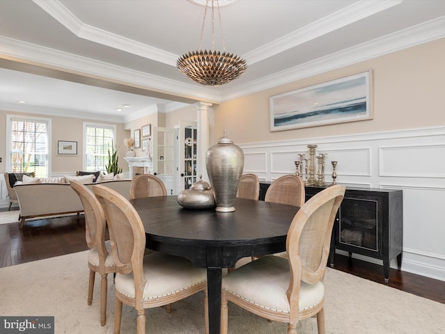 dining space featuring crown molding, a decorative wall, and dark wood-style flooring