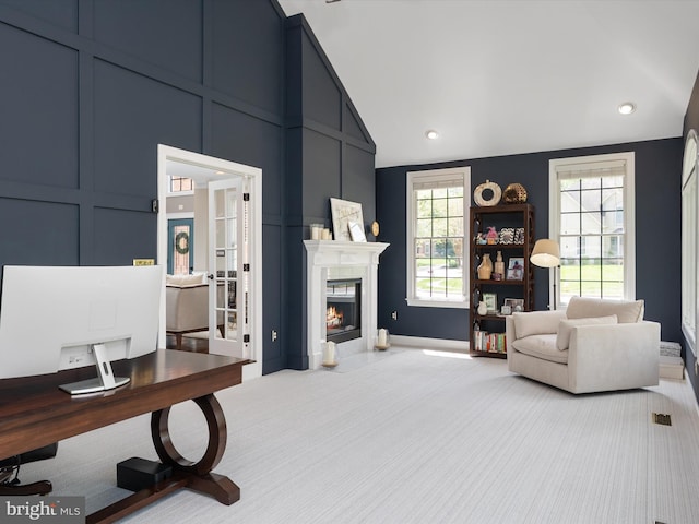carpeted living area with high vaulted ceiling, a decorative wall, and a premium fireplace
