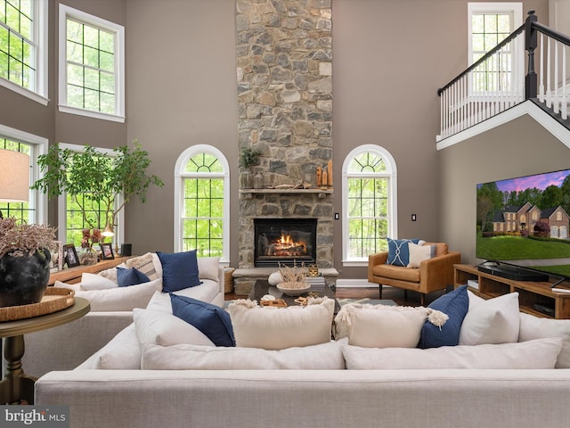 living room featuring a high ceiling and a stone fireplace