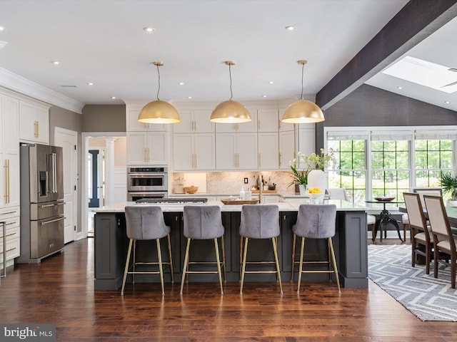 kitchen featuring a large island with sink, tasteful backsplash, white cabinets, and stainless steel appliances