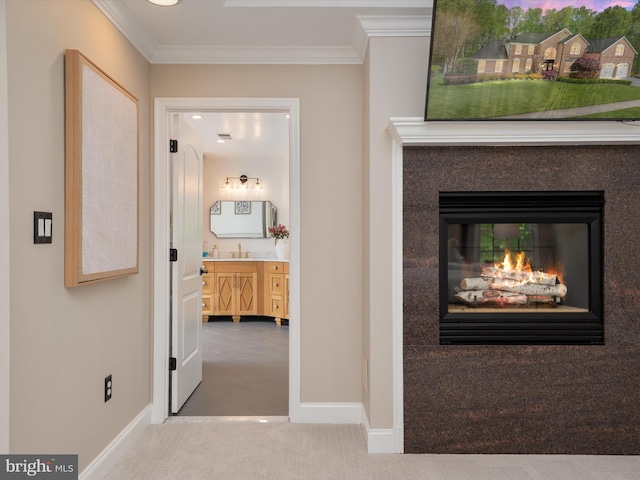 hallway with baseboards, ornamental molding, a sink, and carpet floors