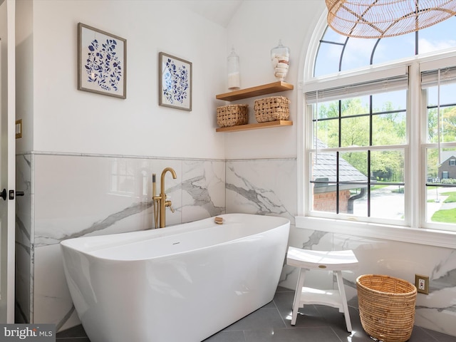 bathroom featuring a wainscoted wall, a freestanding bath, tile patterned floors, and tile walls