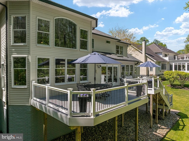 back of property with a shingled roof, a wooden deck, and outdoor dining area
