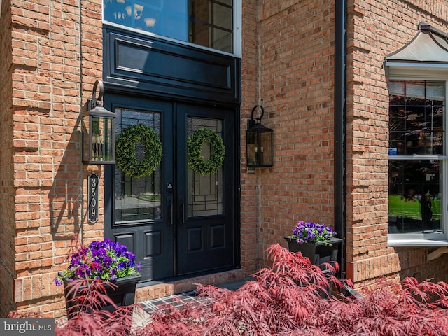 view of exterior entry featuring brick siding and french doors