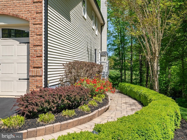 view of side of property featuring an attached garage and brick siding