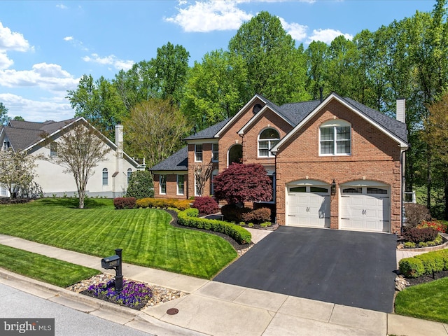 traditional-style home with a front lawn, brick siding, a garage, a chimney, and driveway