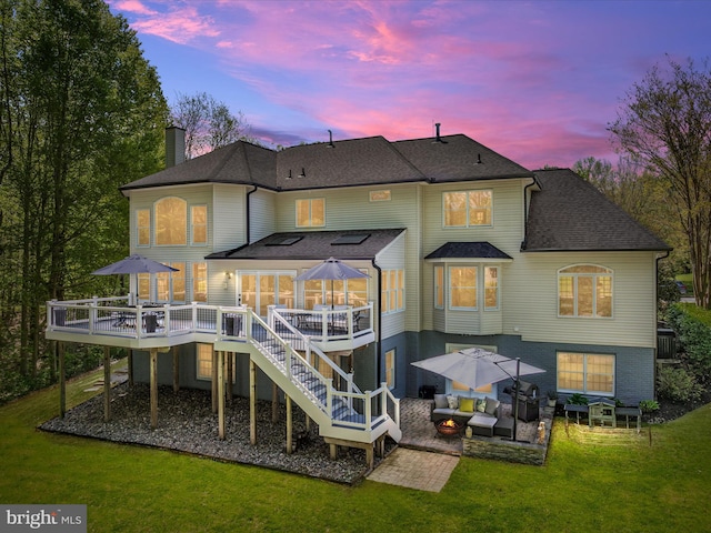 back of house at dusk featuring a lawn, a patio area, an outdoor hangout area, and a deck