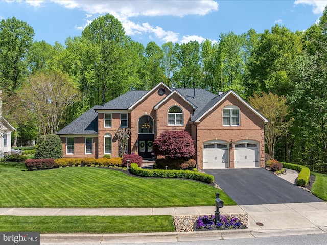 view of front of house with a shingled roof, an attached garage, brick siding, a front yard, and driveway