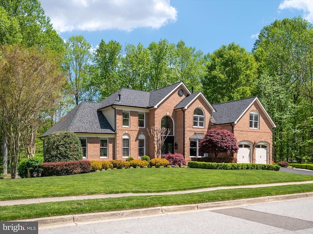 view of front of home with brick siding, a shingled roof, a front yard, and a garage